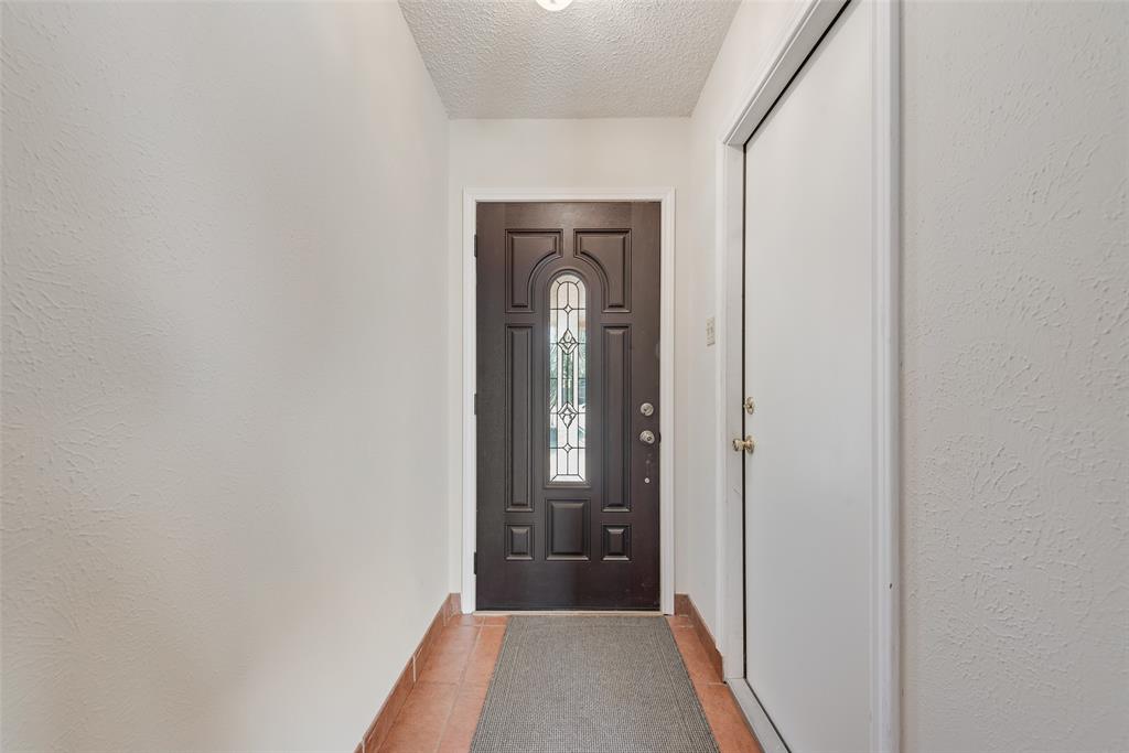703 Rolling Ridge Lane Duncanville, TX 75116 - Photo 7 of 38 Doorway featuring a textured ceiling, a textured wall, and tile patterned flooring