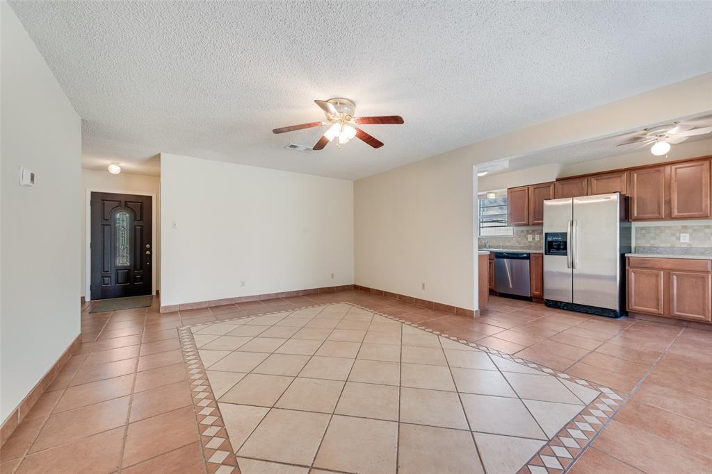 703 Rolling Ridge Lane Duncanville, TX 75116 - Photo 10 of 38 Unfurnished living room featuring a ceiling fan, light tile patterned floors, inlaid floor details, and a textured ceiling