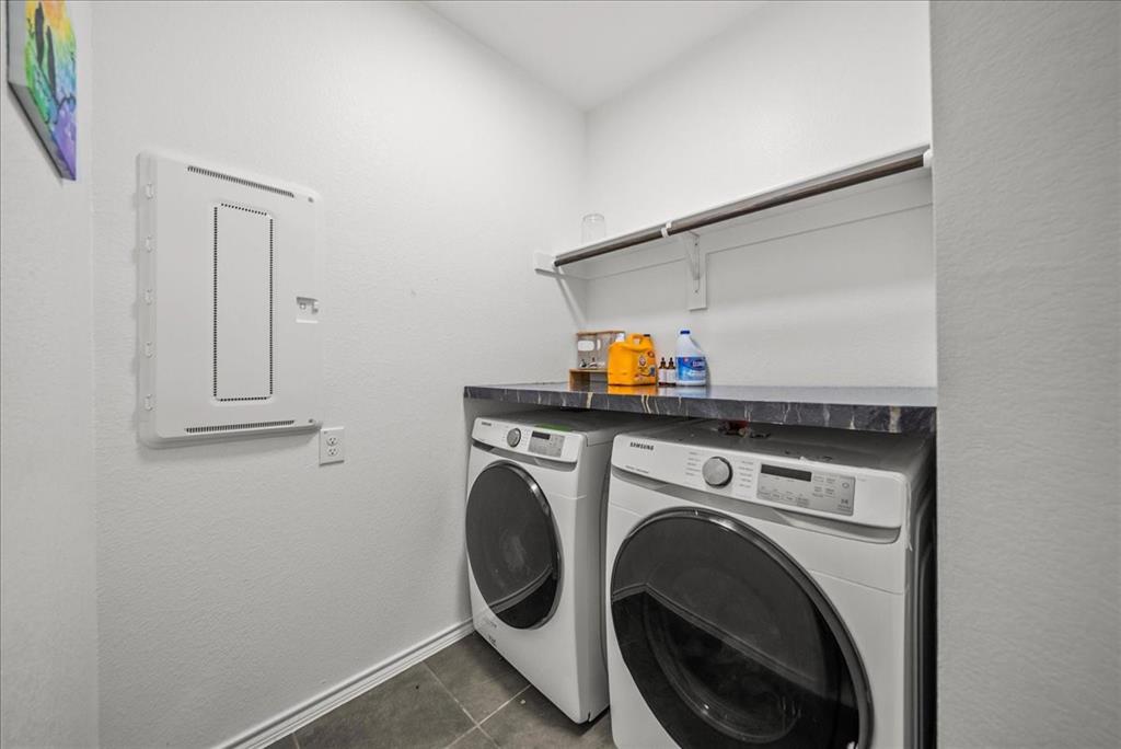 1908 Twisted Tree Lane Mesquite, TX 75149 - Photo 5 of 22 Laundry area with washing machine and clothes dryer, electric panel, dark tile patterned floors, and a textured wall
