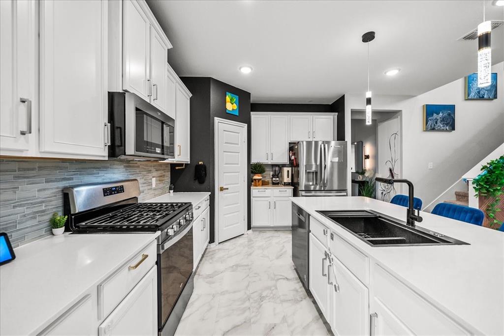 1908 Twisted Tree Lane Mesquite, TX 75149 - Photo 7 of 22 Kitchen featuring stainless steel appliances, light marble finish floors, white cabinetry, pendant lighting, and tasteful backsplash