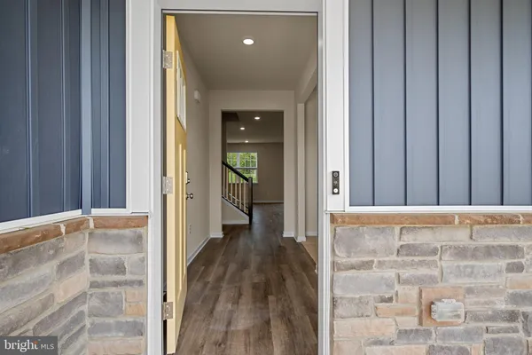 a view of a hallway with wooden floor and a bathroom