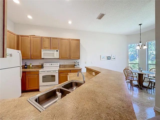 a kitchen with a stove a refrigerator and chairs