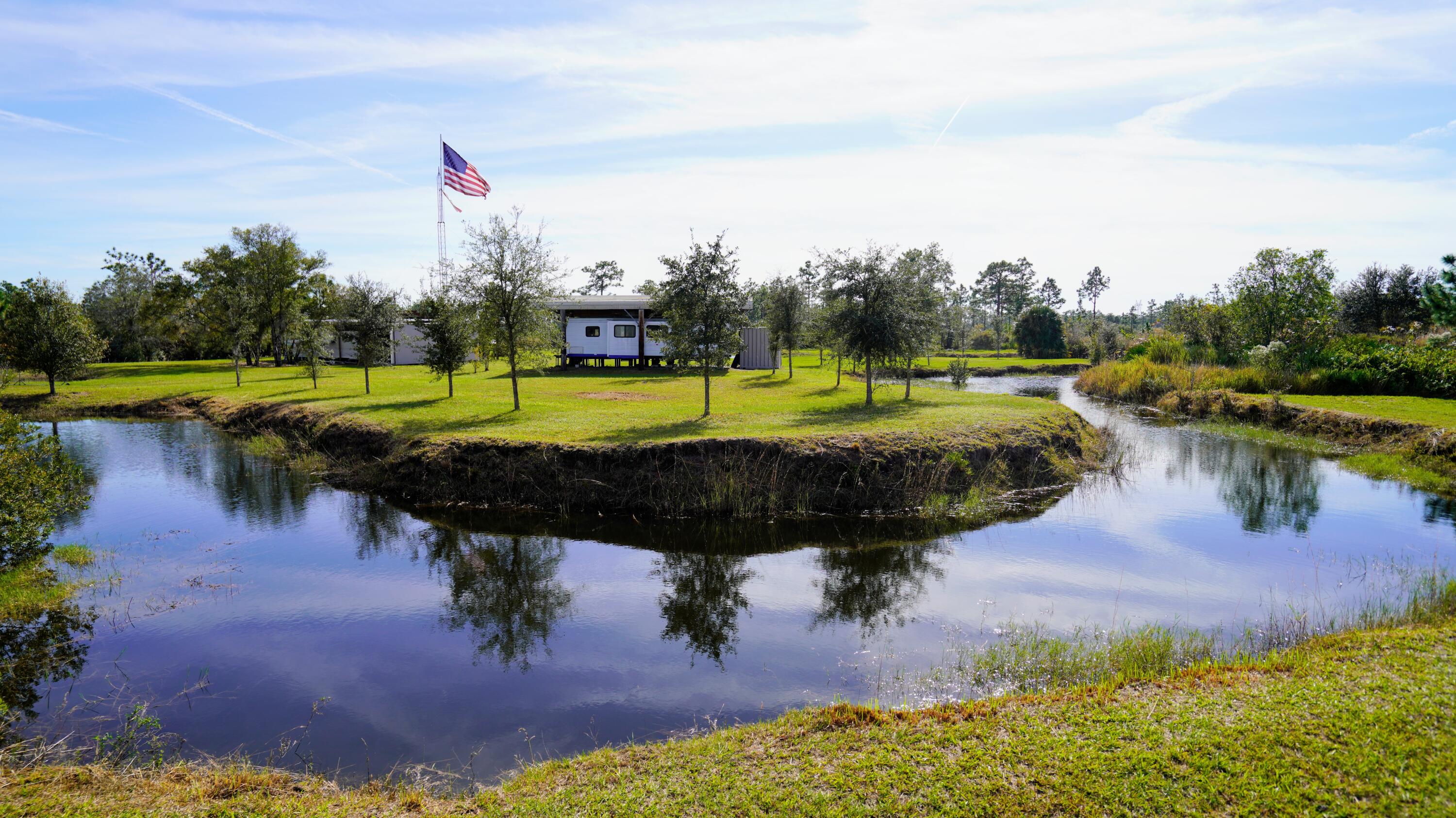 1224001 Holopaw Groves Rd Street St. Cloud, FL 34773 - Photo 2 of 99 a view of a lake with a yard and large trees