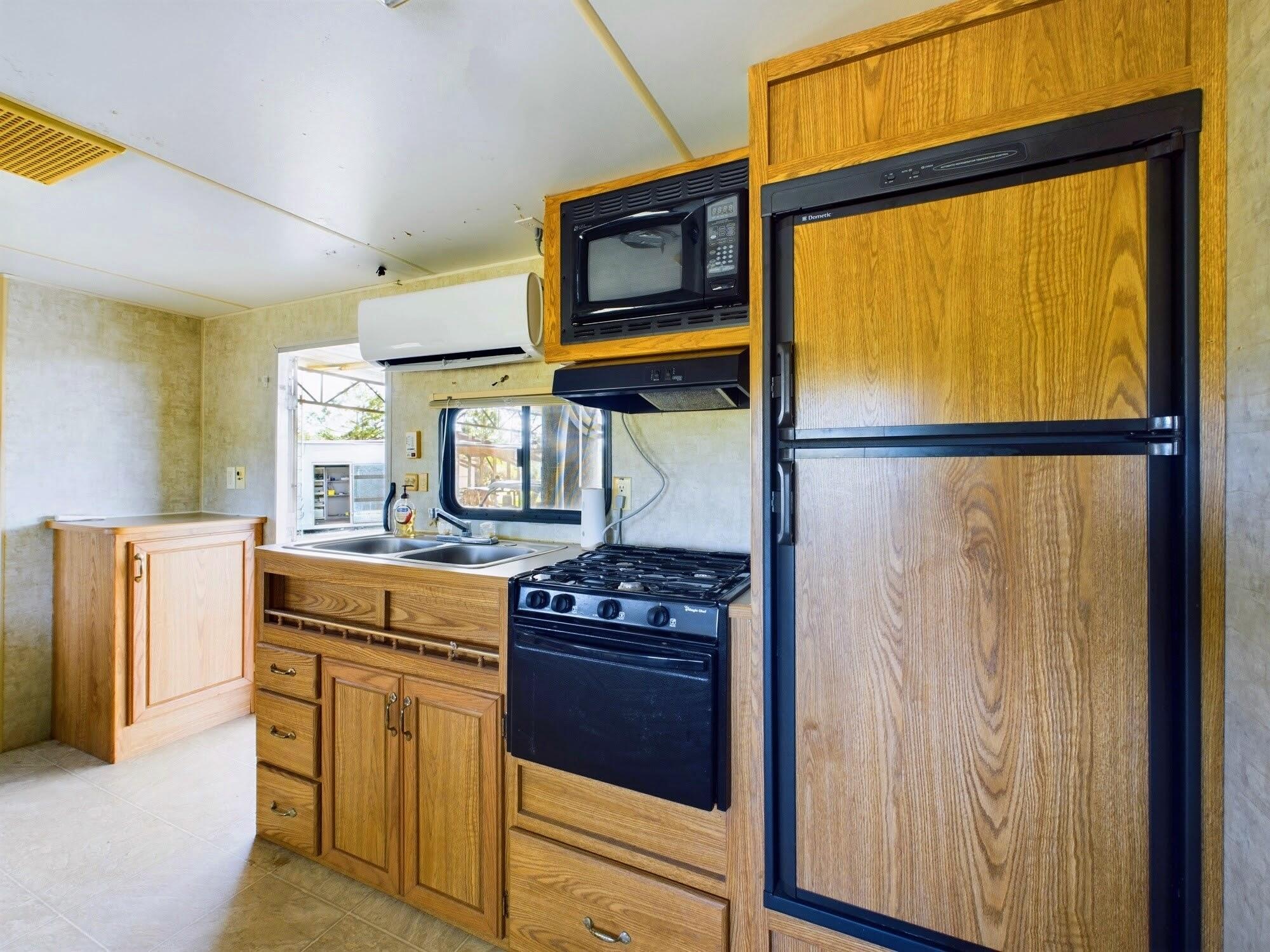 1224001 Holopaw Groves Rd Street St. Cloud, FL 34773 - Photo 23 of 99 a kitchen with stainless steel appliances granite countertop a stove a refrigerator and a stove top oven