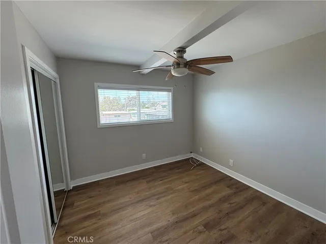 an empty room with wooden floor fan and windows