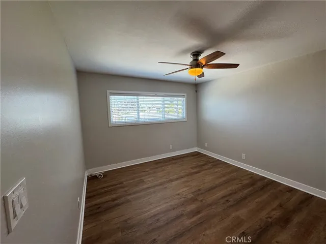 an empty room with wooden floor ceiling fan and windows