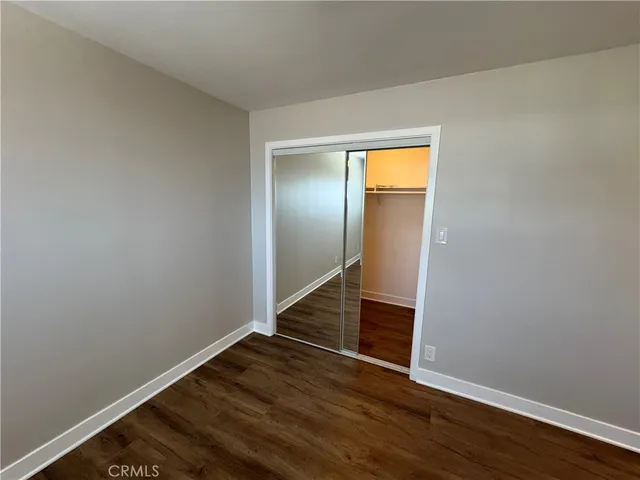 a view of an empty room with wooden floor and closet