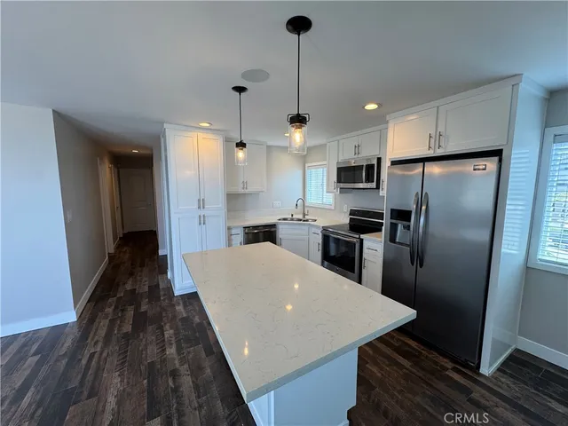 a kitchen with stainless steel appliances a refrigerator a stove a sink dishwasher a oven with a island and cabinets