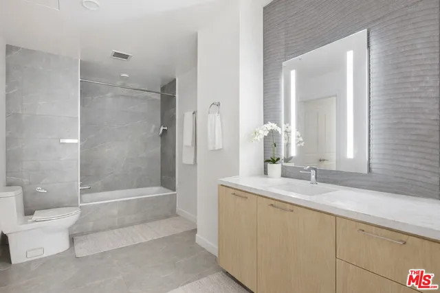 a bathroom with a granite countertop sink a toilet and bathtub