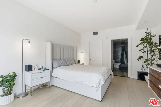 a bedroom with a large bed and potted plant