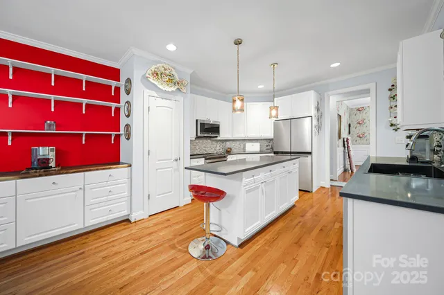 a kitchen with stainless steel appliances granite countertop a refrigerator a sink dishwasher a stove and white countertops with wooden floor