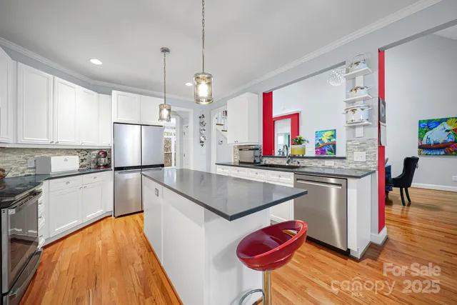 a kitchen with stainless steel appliances granite countertop a sink a stove and a wooden floors