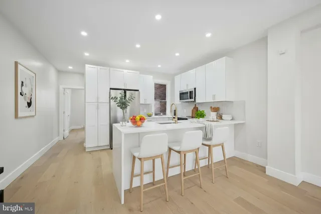 a kitchen with a dining table chairs refrigerator and white cabinets