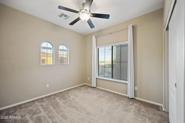 an empty room with windows and fan