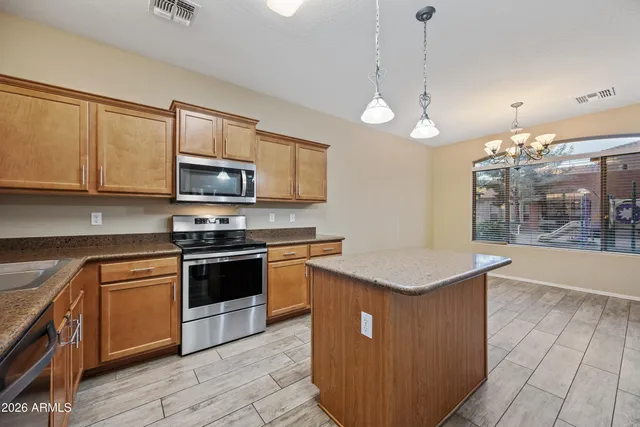 a kitchen with stainless steel appliances granite countertop a stove a sink dishwasher and a microwave oven with cabinets