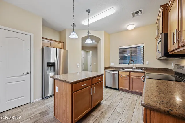 a kitchen with kitchen island granite countertop a sink stove and refrigerator