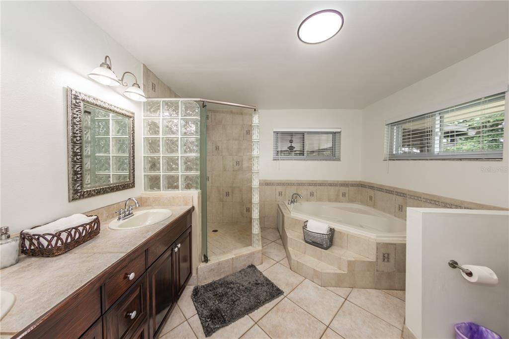 5584 North Dean Road Orlando, FL 32817 - Photo 25 of 39 a spacious bathroom with a granite countertop sink a toilet a mirror and shower