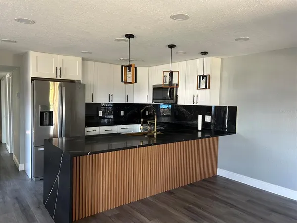 a kitchen with stainless steel appliances granite countertop a refrigerator a sink a stove and wooden floors