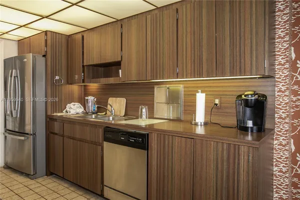 a kitchen with granite countertop a sink stainless steel appliances a refrigerator and a counter