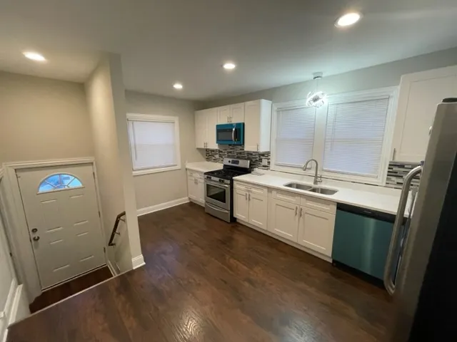 a kitchen with stainless steel appliances granite countertop a sink cabinets and wooden floor