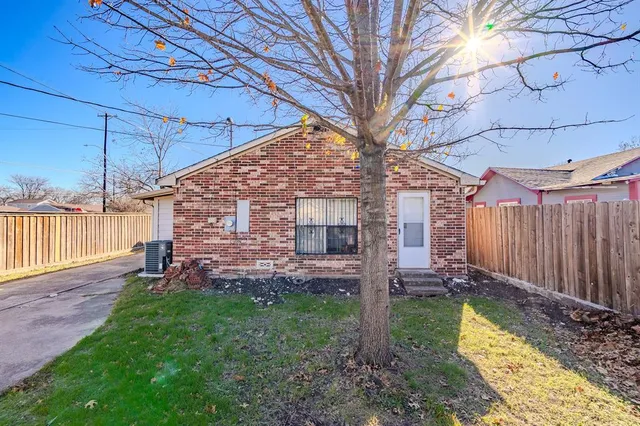 a view of a backyard with wooden fence and a large tree
