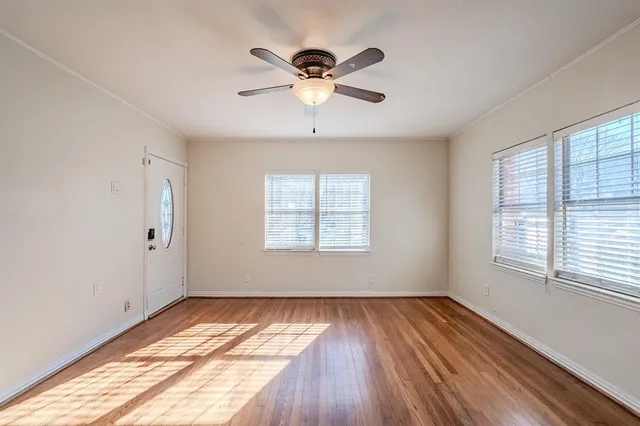 a view of empty room with wooden floor and fan