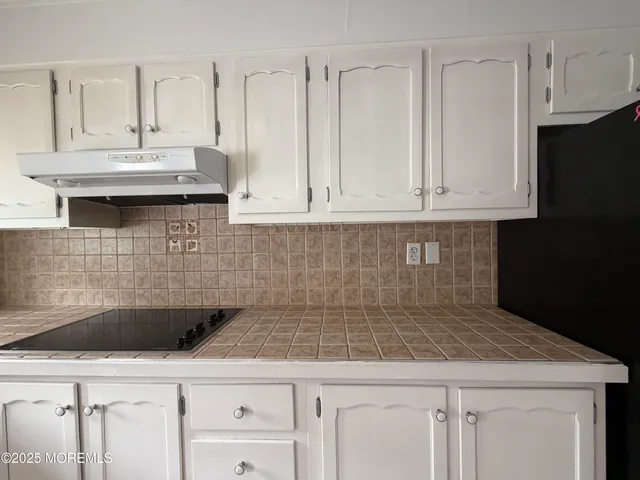a kitchen with stainless steel appliances granite countertop a sink a stove and white cabinets
