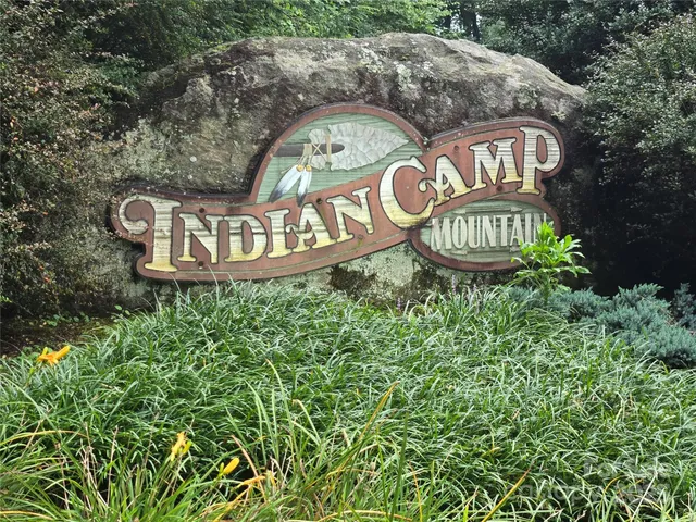 a view of sign board with yard and trees around