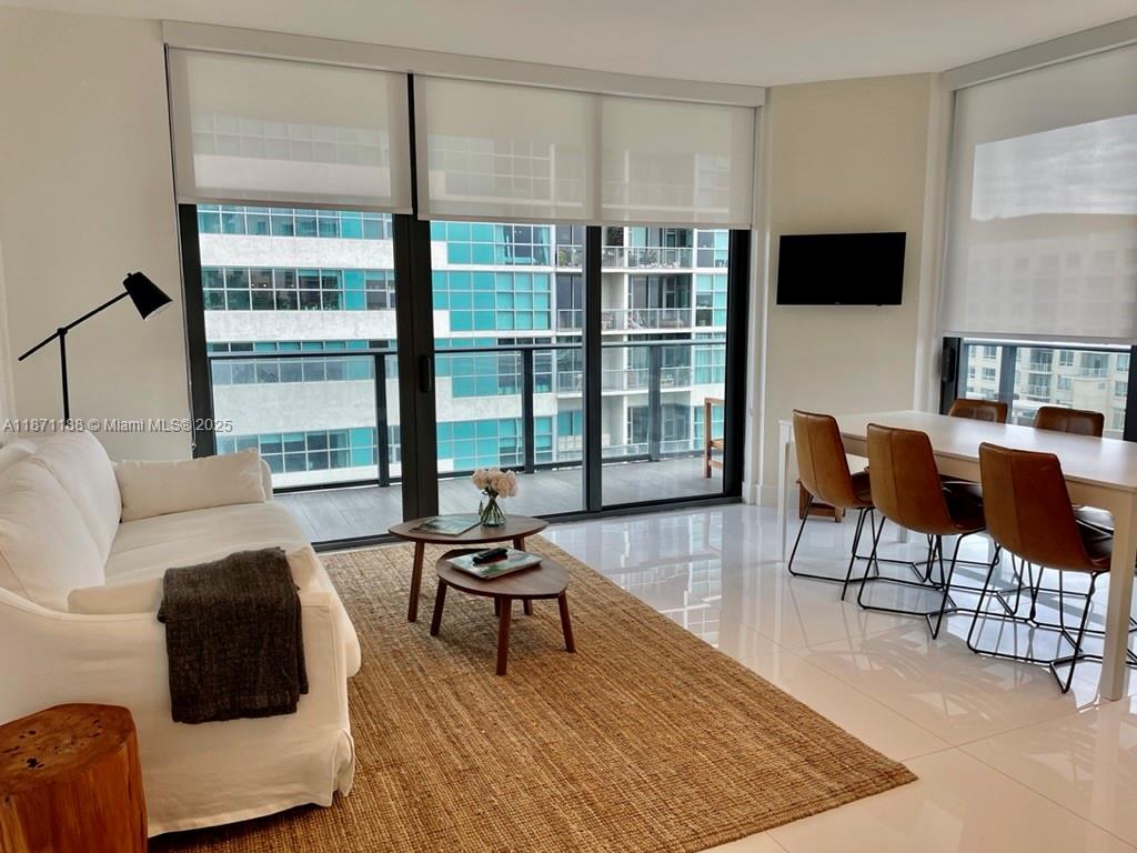 121 Northeast 34th Street, Unit 901 Miami, FL 33137 - Photo 4 of 29 a living room with furniture and a flat screen tv