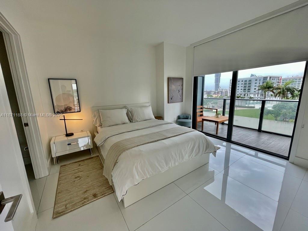 121 Northeast 34th Street, Unit 901 Miami, FL 33137 - Photo 6 of 29 a bedroom with a bed and large mirror next to a large window