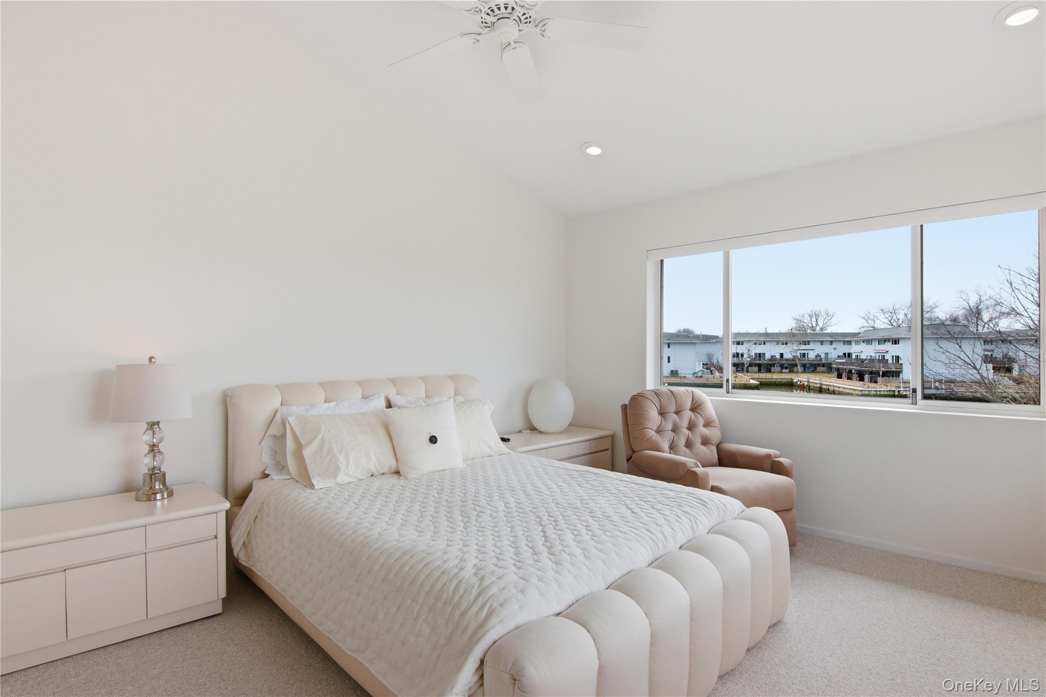 23 Library Avenue, Unit 1 Westhampton Beach, NY 11978 - Photo 15 of 24 Bedroom featuring vaulted ceiling, light colored carpet, a ceiling fan, and recessed lighting with views of the village and water