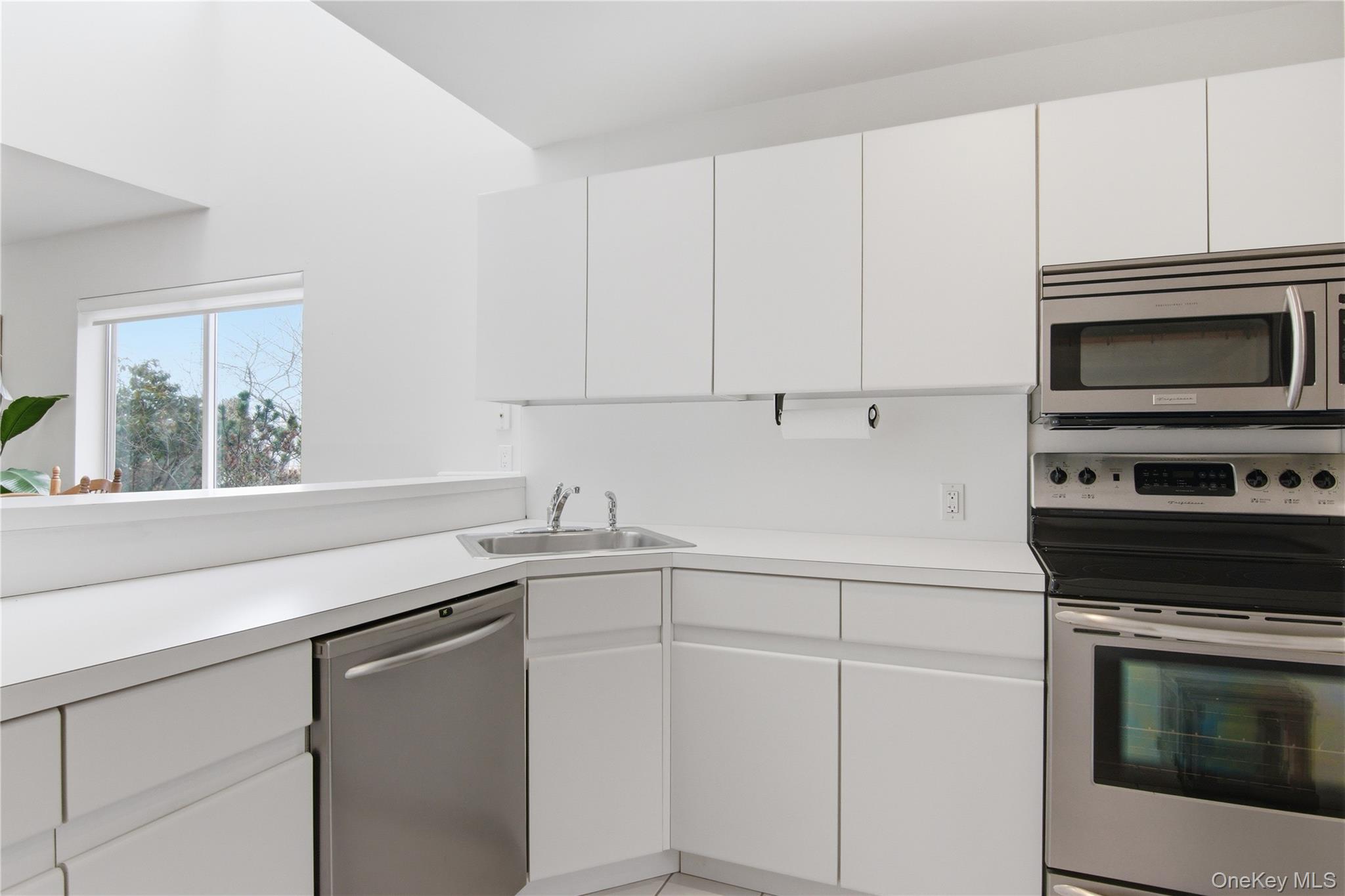 23 Library Avenue, Unit 1 Westhampton Beach, NY 11978 - Photo 4 of 24 Kitchen with stainless steel appliances, light countertops, and white cabinets