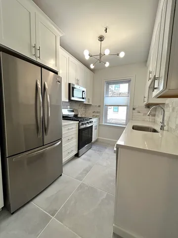a kitchen with granite countertop stainless steel appliances a refrigerator cabinets and a sink