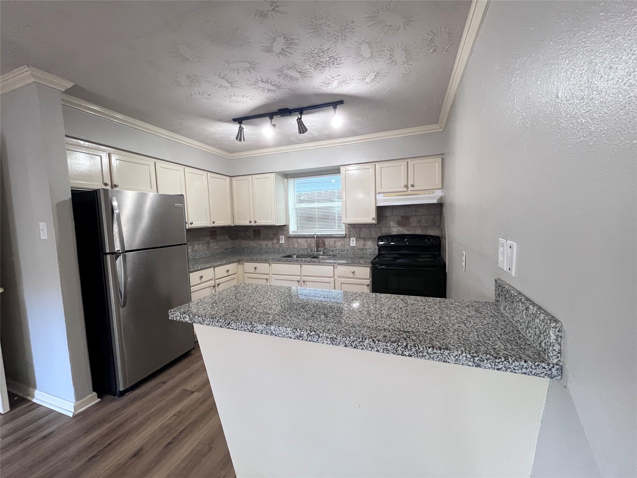 a kitchen with granite countertop a refrigerator and a sink