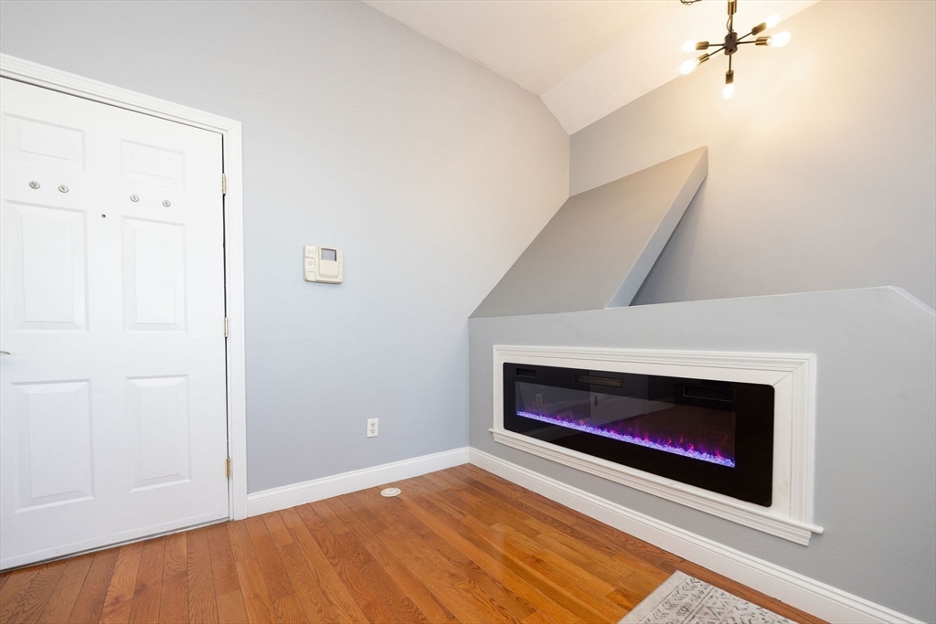 32 Providence Street, Unit 5 Worcester, MA 01604 - Photo 10 of 42 a view of an empty room with wooden floor and a fireplace