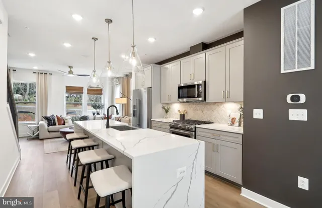 a kitchen with stainless steel appliances kitchen island granite countertop a stove a sink a oven a dining table and chairs with wooden floor