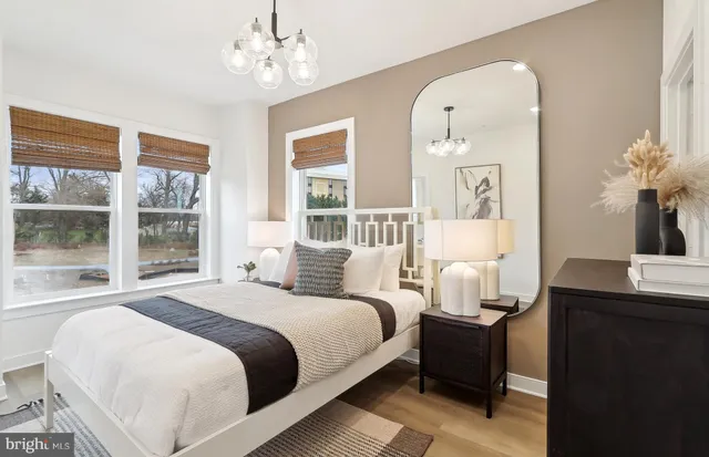 a bedroom with bed a table and windows