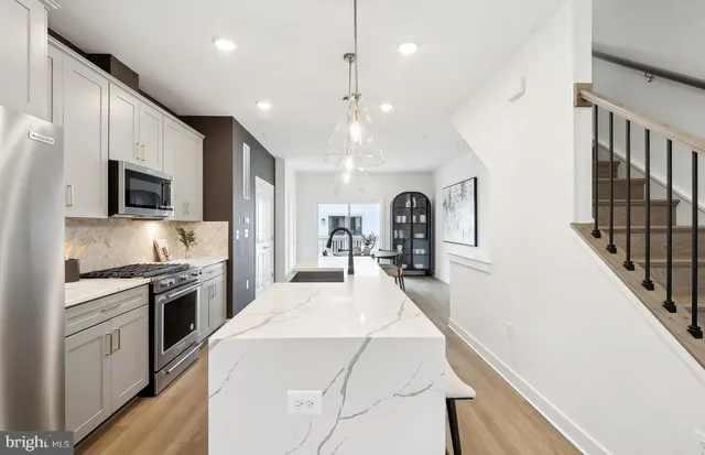 a large kitchen with kitchen island a large counter top space a sink stainless steel appliances and cabinets