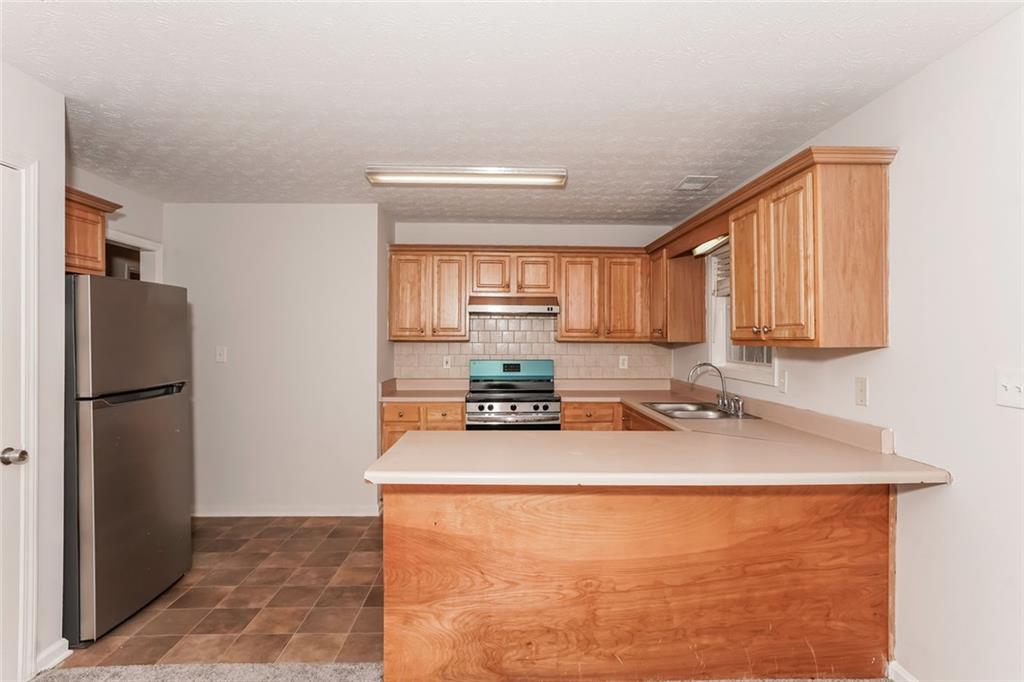 1024 Miss Amber Way Locust Grove, GA 30248 - Photo 8 of 25 a kitchen with a refrigerator a stove a sink and a cabinets