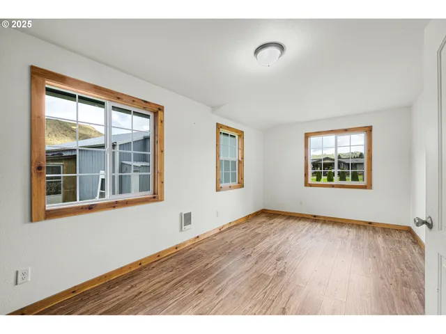 a view of an empty room with a window and wooden floor