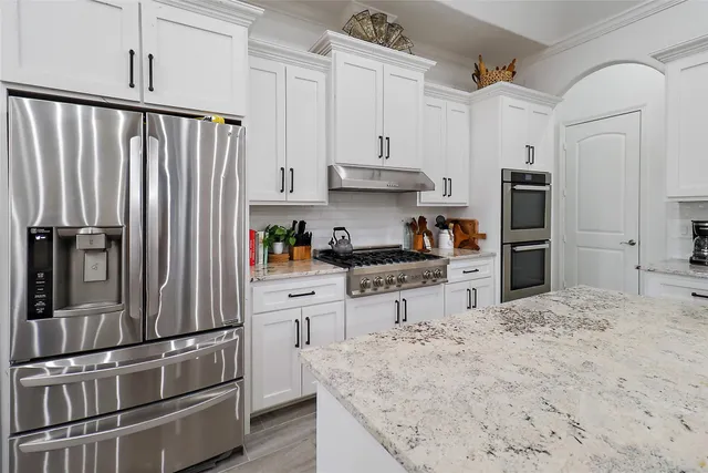 a kitchen with stainless steel appliances granite countertop a refrigerator and a stove top oven