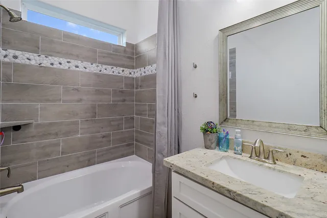 a bathroom with a granite countertop bathtub shower sink and vanity