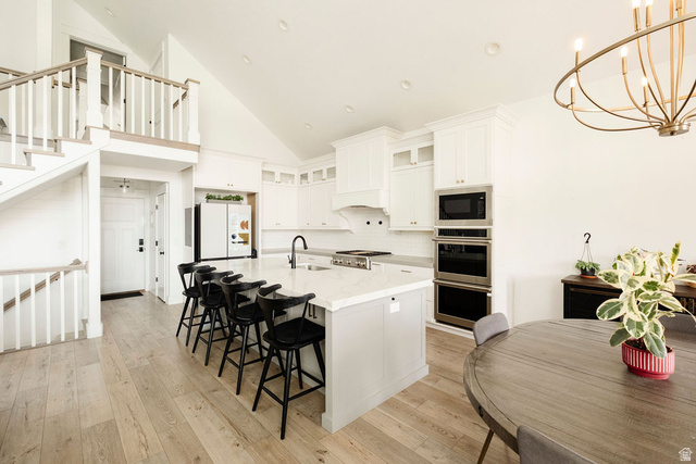 924 Country Lane Farmington, UT 84025 - Photo 11 of 91 Gourmet kitchen featuring a large island with seating, stainless steel appliances, white cabinetry, and wood-finish flooring