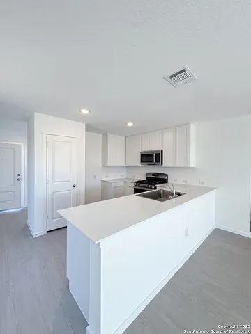 a kitchen with kitchen island a sink stove and white cabinets