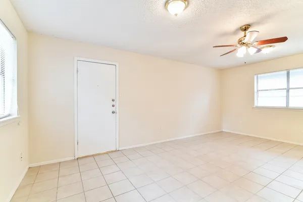 an empty room with windows and fan