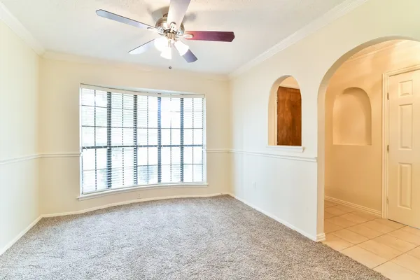 an empty room with chandelier fan and windows