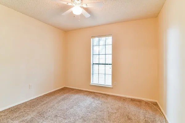 an empty room with windows and fan