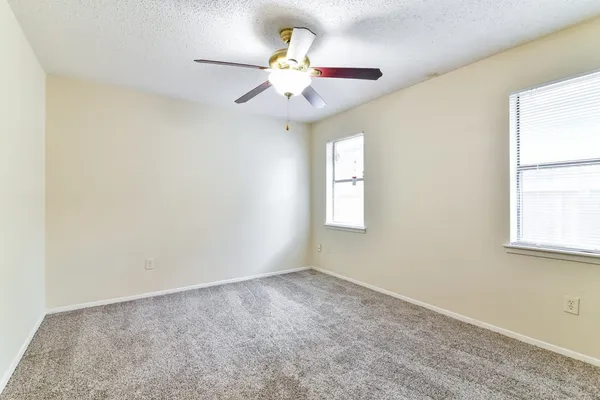 an empty room with windows and fan