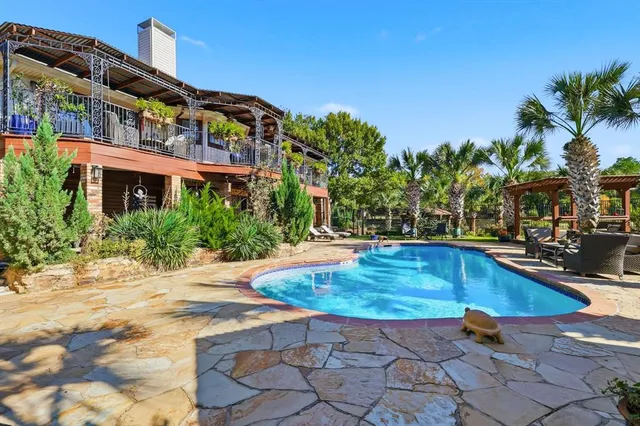 a view of a swimming pool with a table and chairs under an umbrella
