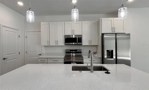 a kitchen with white cabinets and appliances